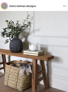 a table with a basket, candle and vase on it next to a wooden bench