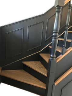 the stairs are made of wood and have metal railings on each handrail, along with black painted paneling