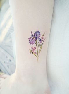 a purple flower tattoo on the ankle