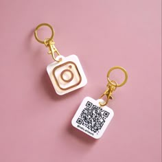 two keychains with a qr code on them sitting next to each other