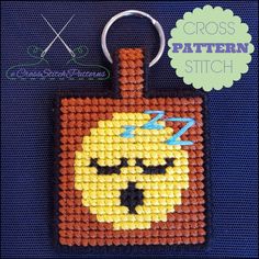 a cross stitch keychain with an orange and yellow square on it's face