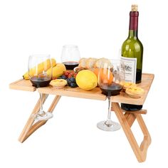 a wooden table topped with glasses of wine and fruit next to a bottle of wine