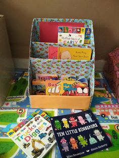 the children's books and toys are on the floor next to the toy box