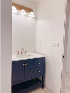 an empty bathroom with two sinks and lights on the wall above it is seen in this image