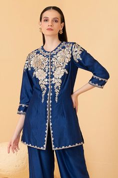 Blue chanderi long top featuring zari embroidered floral motifs embellished with sequins. Comes with palazzo.
Components: 2
Pattern: Embroidered
Type Of Work: Zari, Pearl, Sequin
Neckline: Mandarin Collar
Sleeve Type: Three quarter
Fabric: Chanderi
Color: Blue
Other Details: 
Attached lining
Length: Top sleeve: 18 inches
Weight: 1.5 kgs
Closure: Long Top: Hook
Occasion: Cocktail,Reception - Aza Fashions