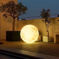 a large white ball sitting on top of a wooden floor next to two planters