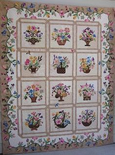 a quilted wall hanging with vases and flowers on it's sides,