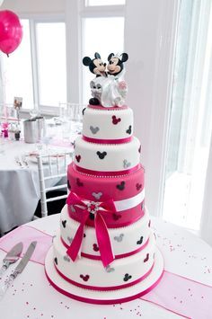 a three tiered cake with mickey and minnie mouse decorations on it's top