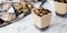 two cups filled with dessert sitting on top of a marble counter next to other food items