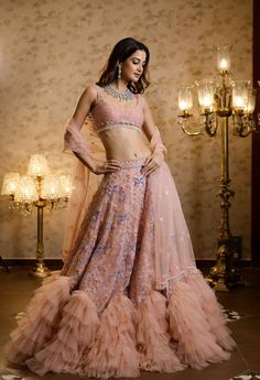 Peach hued lehenga set featuring all over star, butterfly and floral motifs with hints of pink, peach and lavender. The lehenga has a dramatic frill at the bottom and paired with an embellished strappy blouse and matching dupatta.From Isa by Dolly Wahal's Fiori collection.DELIVERY TIMEPlease allow 8-12 weeks for your outfit to arrive.FABRIC DETAILSNetProfessional cleaning only. Frill Lehenga, Strappy Blouse, Indian Fashion Designers, Star Butterfly, Pernia Pop Up Shop, 12 Weeks, Pink Peach, Bridal Lehenga, Floral Motifs