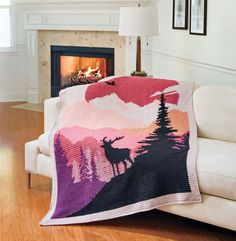 a living room with a couch, fireplace and blanket on the floor in front of it