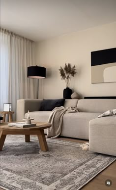 a living room filled with furniture next to a window covered in white drapes and curtains