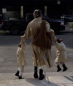 a woman and two children are walking down the street with their back to the camera