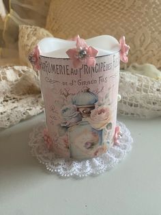 a cup with pink flowers on it sitting on a doily