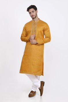 Vibrant mustard yellow illuminates the kurta, as delicate gold leaves and embroidery bloom like sunrise. Intricate cuffs and neckline sparkle with subtle luxury, as the fabric tells a tale of refined elegance. Paired with crisp white pyjama, the ensemble radiates a warm sophistication, perfect for the modern man who wears his grace with a touch of vintage charm, shining bright like a golden dawn. * Pre stitched short kurta  for special occasions. * Tailored in premium quality fabric. * Full sleeved  kurta. * Adorned with mandarin collar and sequins. * Dry clean only to maintain colour and quality.    Note: Colors may slightly vary due to photographic lighting.    Please contact us if you have any questions via email, social media, text or whatsapp message on 425-698-9400. Festive Gold Kurta With Naqshi Detail, Festive Gold Kurta With Naqshi, Gold Naqshi Straight Kurta, Gold Kurta With Gold Embroidery For Eid, Festive Gold Kurta With Gold Embroidery, Gold Naqshi Kurta For Diwali, Gold Kurta For Eid, Diwali Yellow Sets With Gold Embroidery, Yellow Naqshi Kurta For Eid