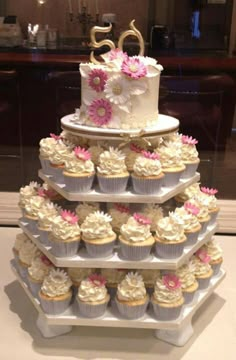 a three tiered cake with cupcakes on it