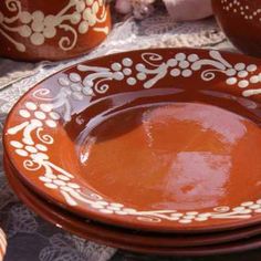 an orange and white plate sitting on top of a table next to two brown vases