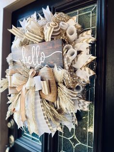 a wreath with the word hello on it is hanging on a black door handle and decorated with burlap ribbons