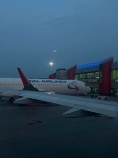 an airplane is parked at the airport with its lights on and it's landing gear down