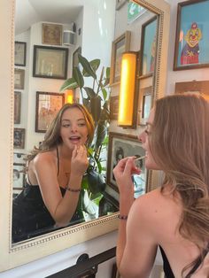 a woman brushing her teeth in front of a mirror while looking at herself in the mirror