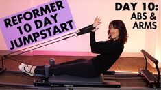 a woman in black shirt sitting on exercise equipment with arms raised and legs crossed, holding up a sign that says reporter 10 day jumpstart