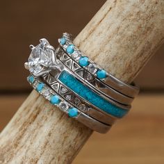 three wedding rings with turquoise stones and diamonds on each ring, sitting on a piece of wood