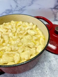 a red pot filled with macaroni and cheese sitting on top of a counter