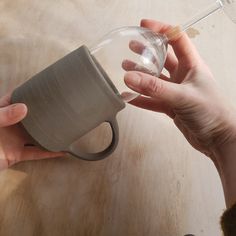 a person holding a coffee cup with their right hand on the top of it, and another persons left hand reaching out