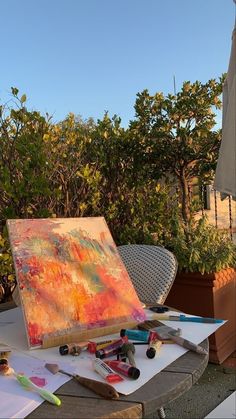 an artist's easel sitting on top of a table filled with paints and pencils