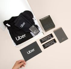 a person is holding up some black and white business cards next to other items on a table