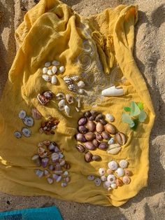 a yellow bag filled with seashells on top of a sandy beach