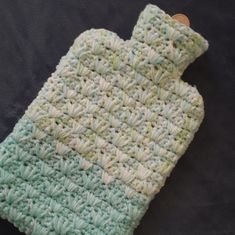 a crocheted green and white dishcloth with a button on the end is laying on a black surface