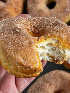 a hand holding a donut with powdered sugar on it's outside and inside