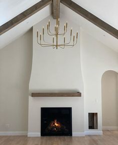 an empty room with a fireplace and chandelier hanging from the ceiling above it