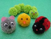 four small stuffed animals sitting next to each other on a green surface with one caterpillar