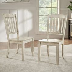 two white chairs sitting next to each other on top of a carpeted floor in front of a window