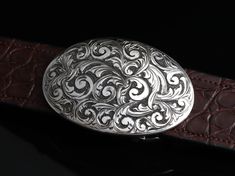 The Sutro Austin by Comstock Heritage is a Sterling silver "Sutro" round shape belt buckle with plenty of style. Hand carved, deep "Austin" Italian style engraving covers the whole piece and it is then antiqued and given an extra shine on the engraving to make it stand out. Measures approximately 2" x 3" Fits up to a 1.5" belt straps Luxury Engraved Silver Belt Buckles, Elegant Silver Engraved Belt, Antique Engraved Belt Buckles For Formal Wear, Vintage Silver Engraved Belt, Elegant Hand Tooled Belt Buckles For Formal Wear, Elegant Hand Tooled Belt Buckles For Formal Occasions, Elegant Formal Hand-tooled Belt Buckles, Vintage Engraved Belt Buckles For Formal Wear, Vintage Engraved Belt Buckles For Formal Occasions