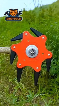 an orange and black tool is in the grass