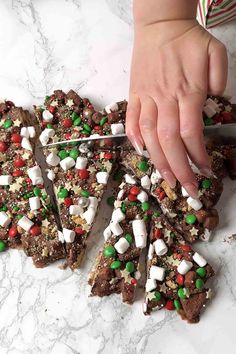 someone is cutting into some christmas treats on a table with candy and marshmallows