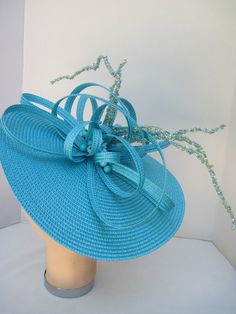 "* This design can be worn on either side of the head and has a sophisticated side tilt. It features a monocromatic color scheme in a tantalizing turquoise. The center of the hat form has a burst of looped and swirled braiding accented by enhanced clusters of matching berries and curly berry twigs. * On an 12\" round flat hat form this is a great design for spring and summer and will also go right into the fall and winter as well. * It is light weight, balanced and comfortable on a white satin c Blue Fitted Fascinator For Beach, Turquoise Fitted Party Hat, Turquoise Fitted Hat For Party, Fitted Turquoise Hat For Party, Elegant Turquoise Fascinator For Kentucky Derby, Elegant Turquoise Fascinator For Wedding, Turquoise Fascinator For Kentucky Derby, Elegant Turquoise Summer Hat, Turquoise Fascinator For Spring Party