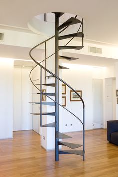 a spiral staircase in the middle of a living room with hardwood floors and white walls