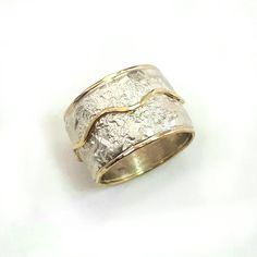 This is a wide, bold ring, chunky but not heavy, that makes a statement. It has a crumpled tinfoil texture with a wavy gold stripe soldered on top. Width: 0.56 inch / 14 mm Thickness: 0.1 inch / 2.5 mm This listing is for sizes 4-13- Just convo me your size. For other sizes - please convo me. Additional information If you liked this item, you may also want to look at these pieces: http://etsy.me/2fWkafJ http://etsy.me/2eI2vT3 For customer reviews of our shop: http://etsy.me/2eOQZZt Back to our s Hammered Wide Band Ring As Gift, Unique Hand Forged Wide Band Jewelry, Wide Band Hand Cast Rings For Anniversary, Elegant Handmade White Gold Wide Band Ring, Anniversary Rings With Hand Cast Wide Band, Anniversary Hand Cast Wide Band Rings, Unique Hammered Wide Band Ring Gift, Unique Hammered Rings With Thick Band, Handmade Wide Band White Gold Jewelry