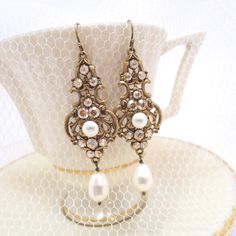 These gorgeous earrings I created with elegant European made antique brass filigree drops in which I placed Swarovski golden shadow crystals and Swarovski ivory pearls. Earrings dangle 2-3/4 inches from top of ear wire to bottom of pearl drop. PLEASE ALLOW APPROX 10 BUSINESS DAYS FOR COMPLETION BEFORE SHIPPING. This is an original design by © Treasures by Agnes Feel free to contact me with any questions ! Thank you for visiting ! Treasures570 Back to main page of Treasures570 for more beautiful Ornate Antique Gold Earrings For Wedding, Victorian Wedding Earrings With Antique Finish, Antique Bronze Earrings For Wedding, Antique Gold Chandelier Earrings For Wedding, Gold Jeweled Pearl Earrings, Antique Finish Bronze Wedding Earrings, Antique Filigree Chandelier Earrings For Wedding, Wedding Bronze Filigree Earrings, Antique Finish Drop Earrings For Wedding