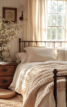 a bedroom with white linens and flowers in the window sill on the bed