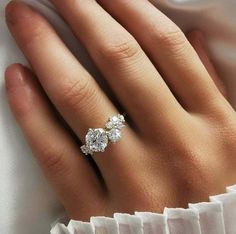 a woman's hand with three diamond rings on top of her finger and white satin