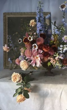 a vase filled with lots of flowers on top of a white tablecloth covered table