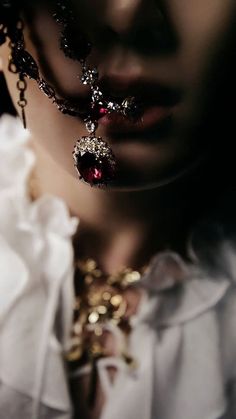 a close up of a person wearing jewelry and looking down at the ground with their face covered by chains