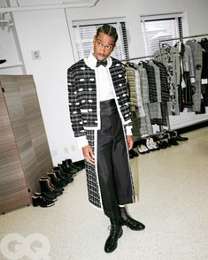 a young man standing in front of a rack of clothes and shoes with his hands on his hips