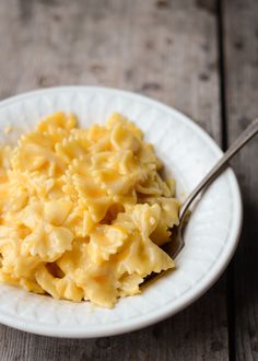 a white bowl filled with macaroni and cheese on top of a wooden table