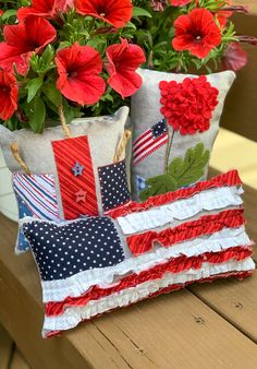 red, white and blue pillows with flowers in them sitting on a wooden table next to a potted plant